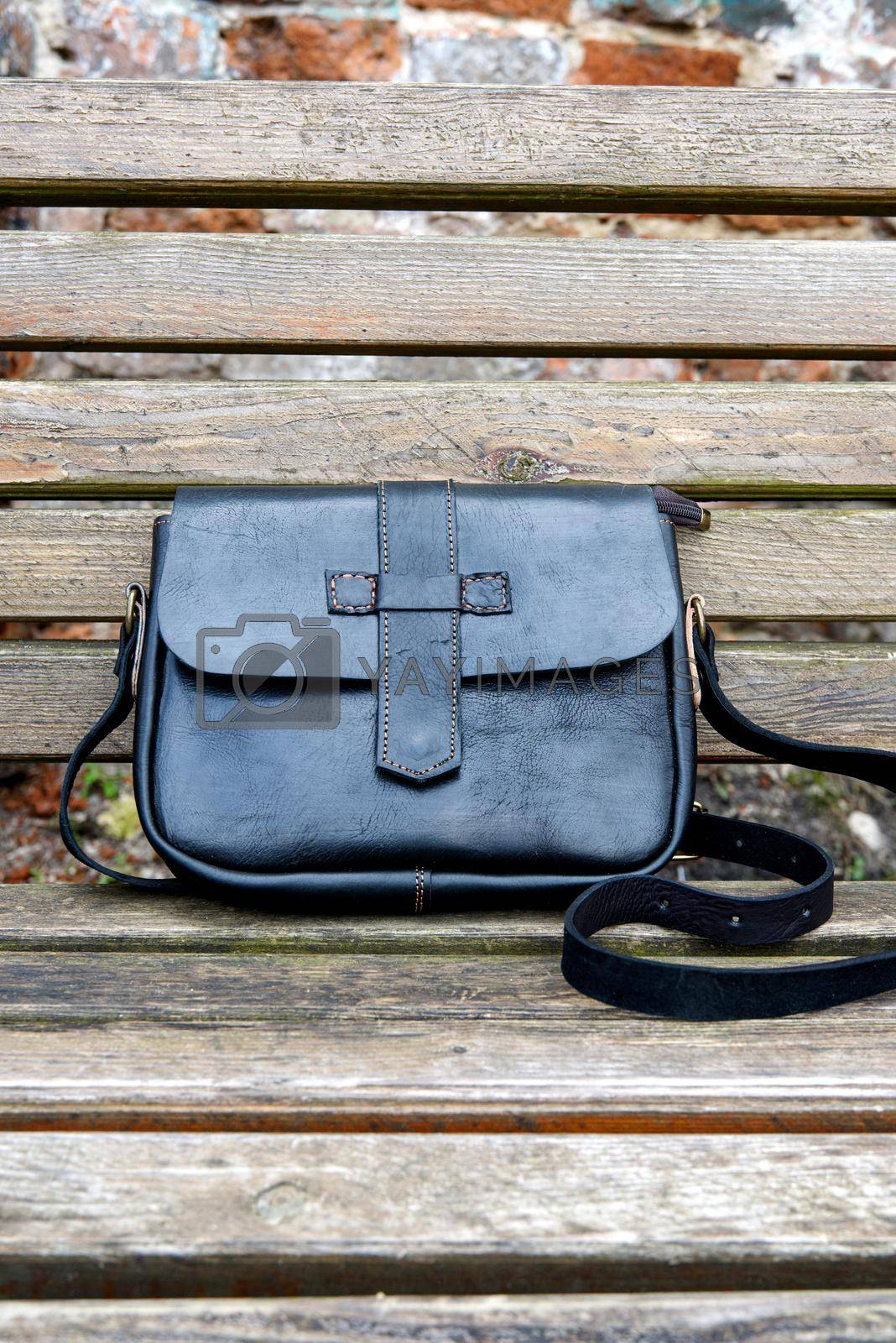 Royalty free image of close-up photo of black leather handbag on a wooden bench by Ashtray25