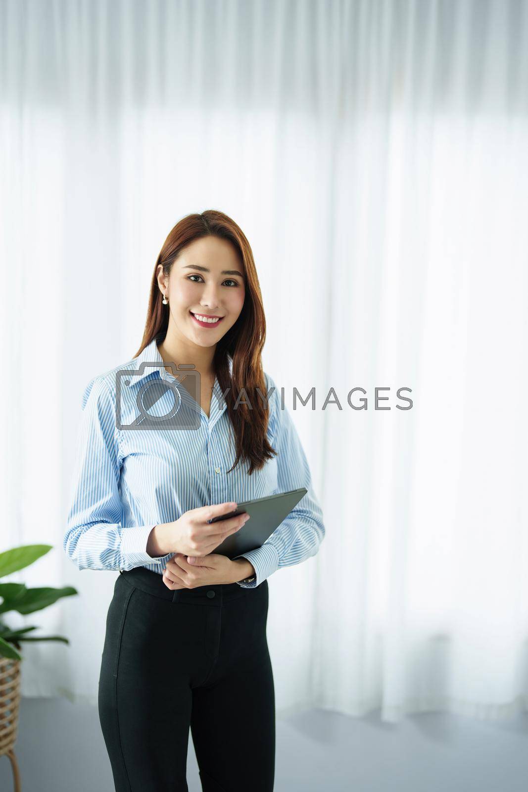 Royalty free image of Entrepreneur, Business Owner, Accountant, Portrait of Starting small businesses Asians holding a smiling tablet in the office. by Manastrong