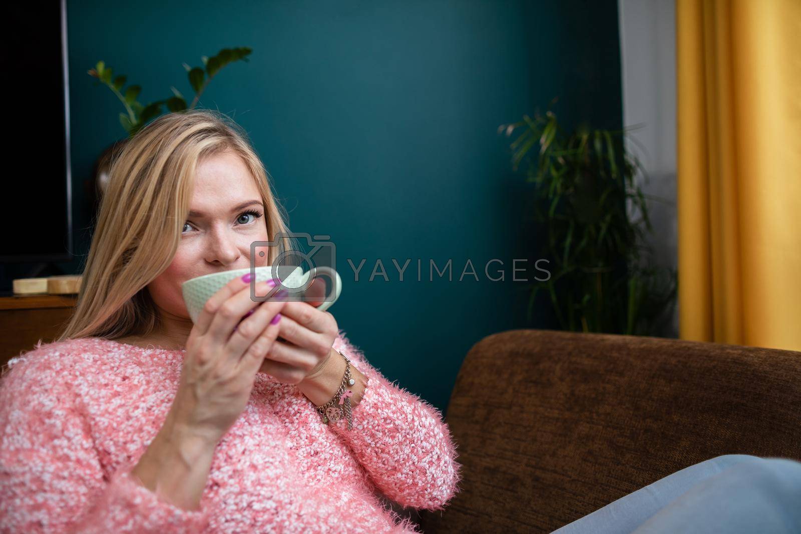 Royalty free image of A young woman drinks coffee while sitting in the living room. by fotodrobik