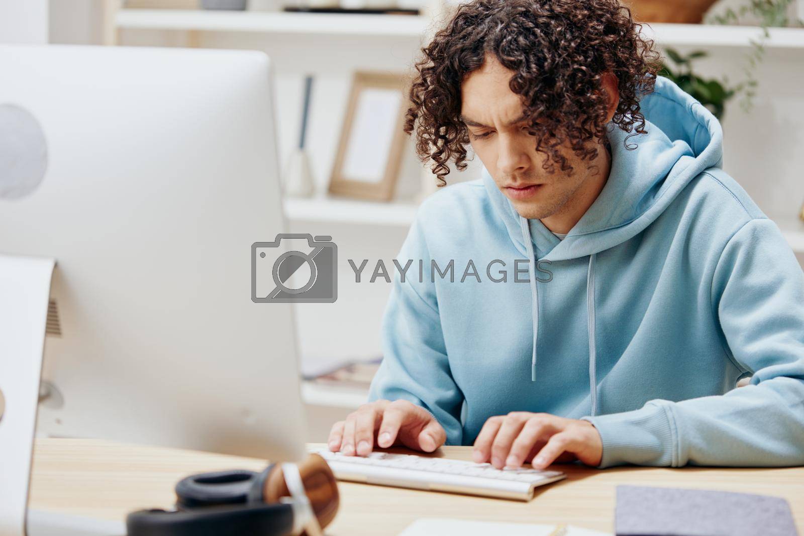 guy with curly hair in a blue jacket in front of a computer Lifestyle. High quality photo