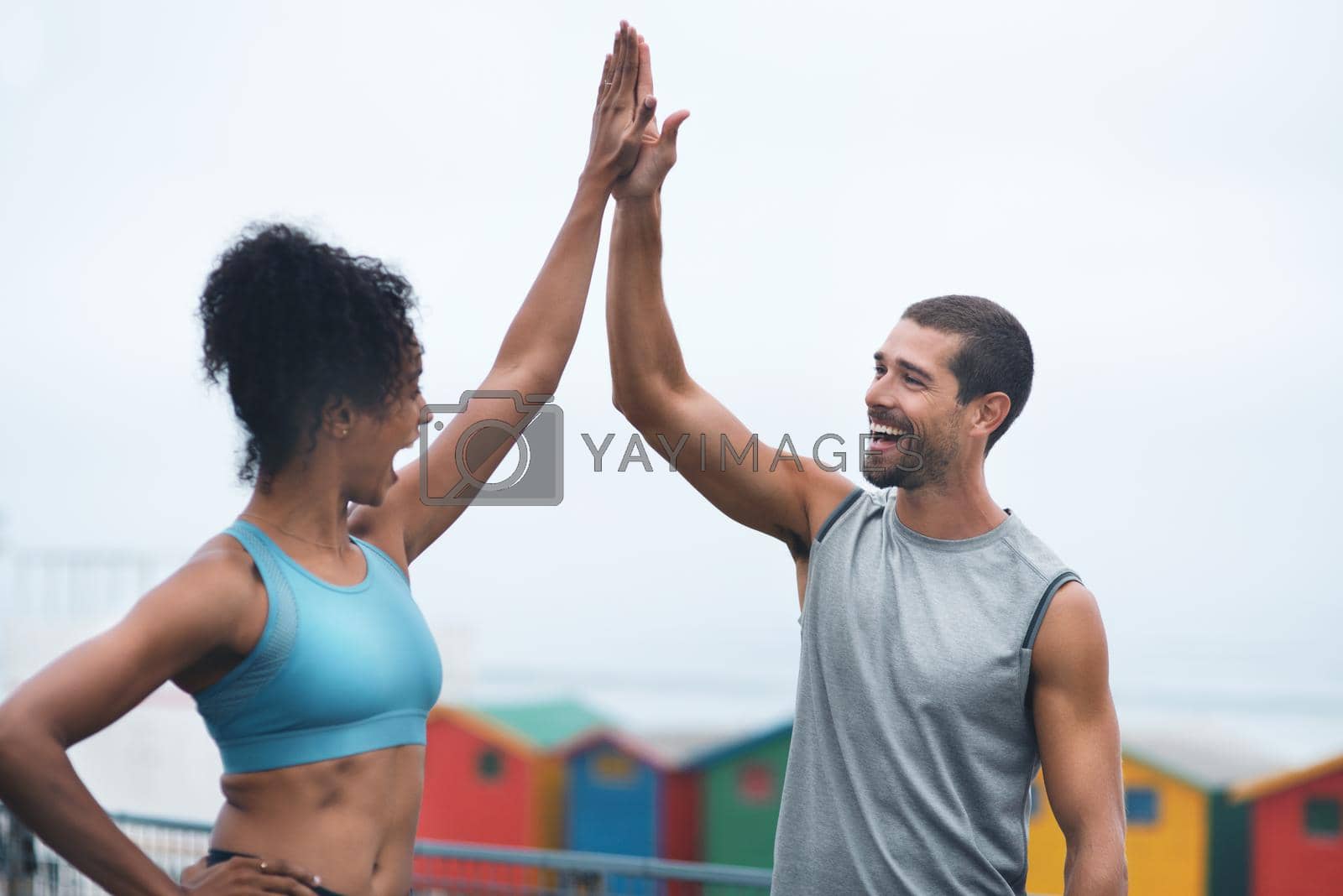 Shot of two sporty young people giving each other a high five while exercising outdoors.