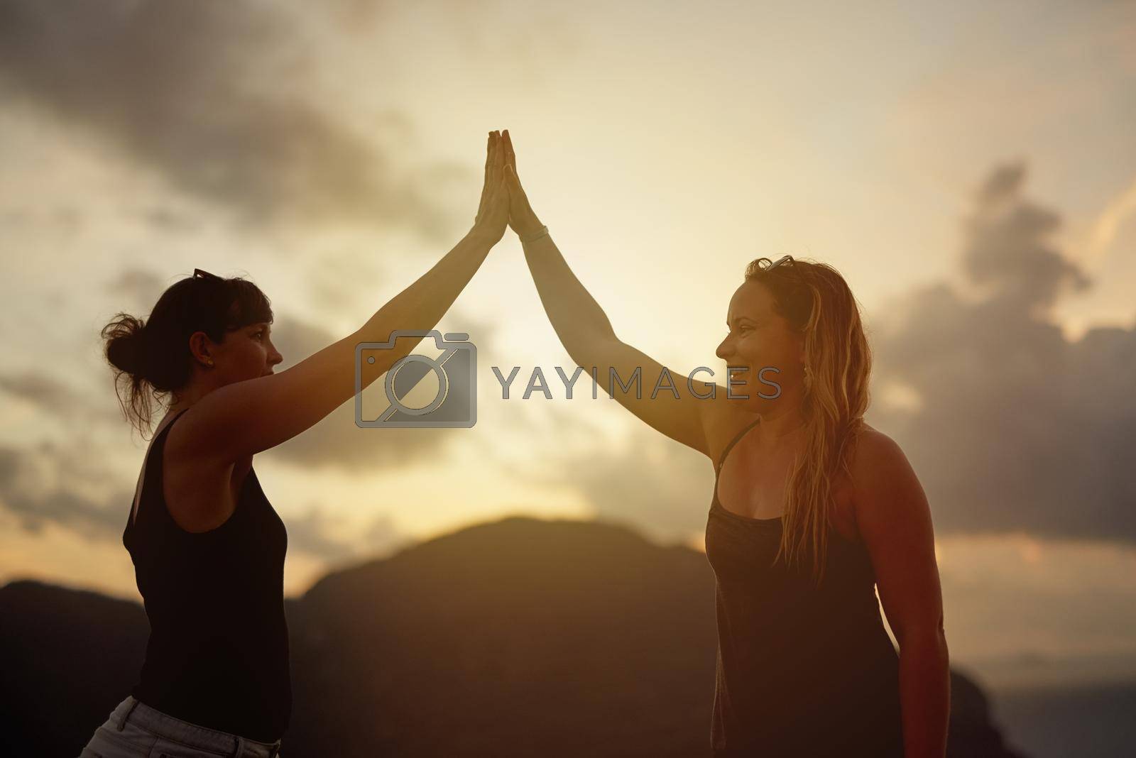Shot of two happy young friends high fiving each other at sunset.