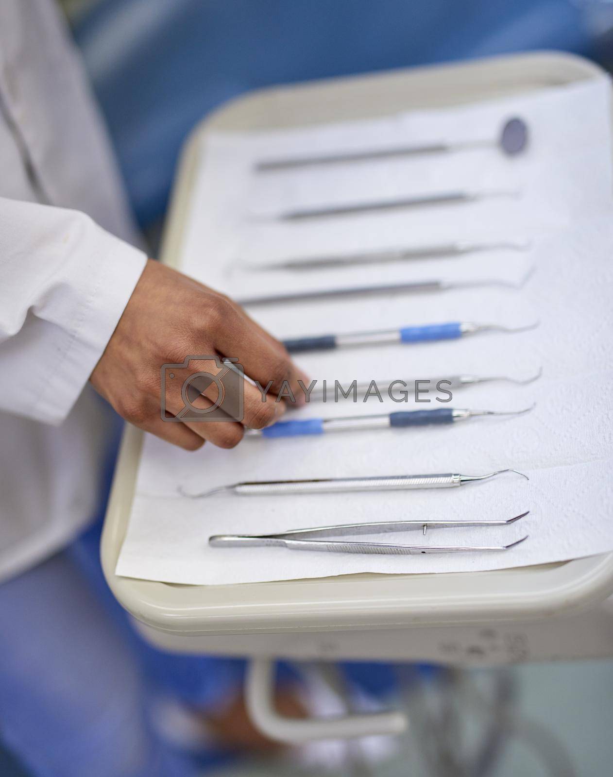 Closeup shot of an unrecognisable dentist working with a tray of surgical instruments.