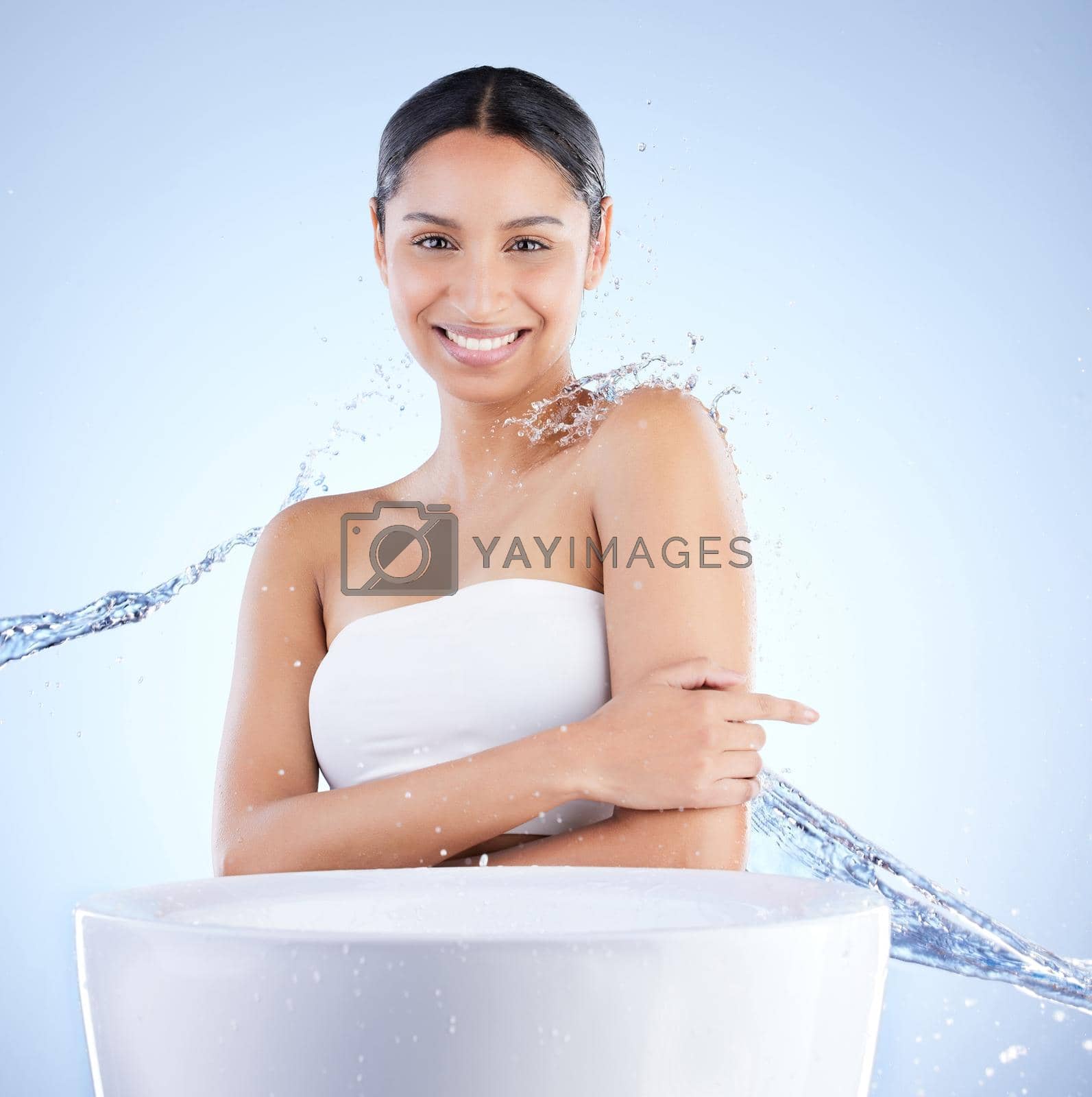 Shot of a young woman washing herself against a blue background.