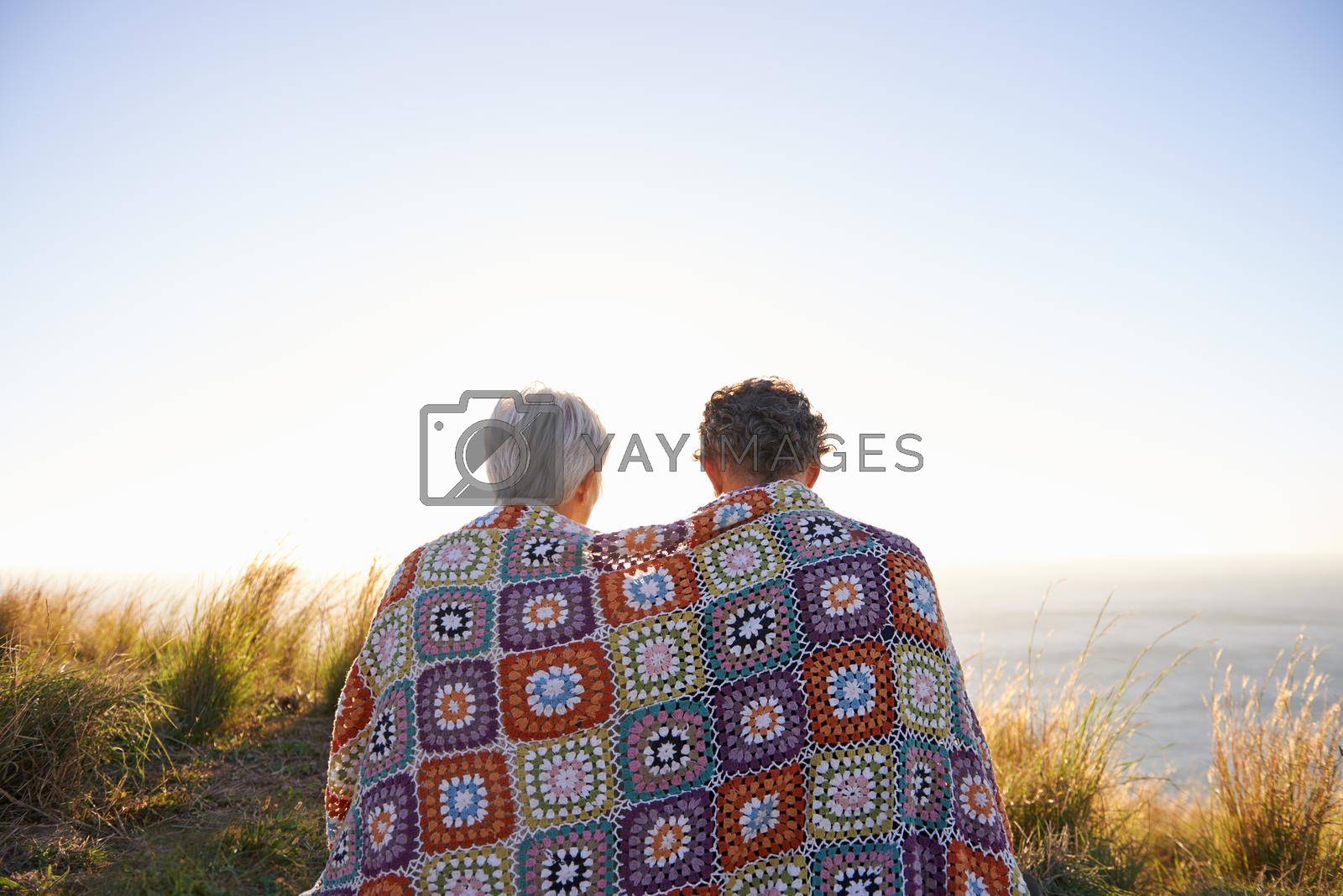 View of a senior couple sitting on a hillside together.
