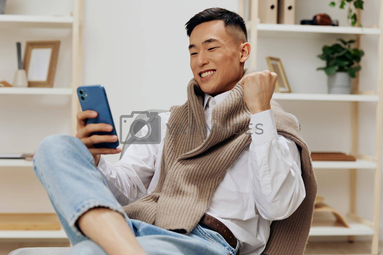Asian man communication with the phone in his hands sits on a chair interior technologies. High quality photo