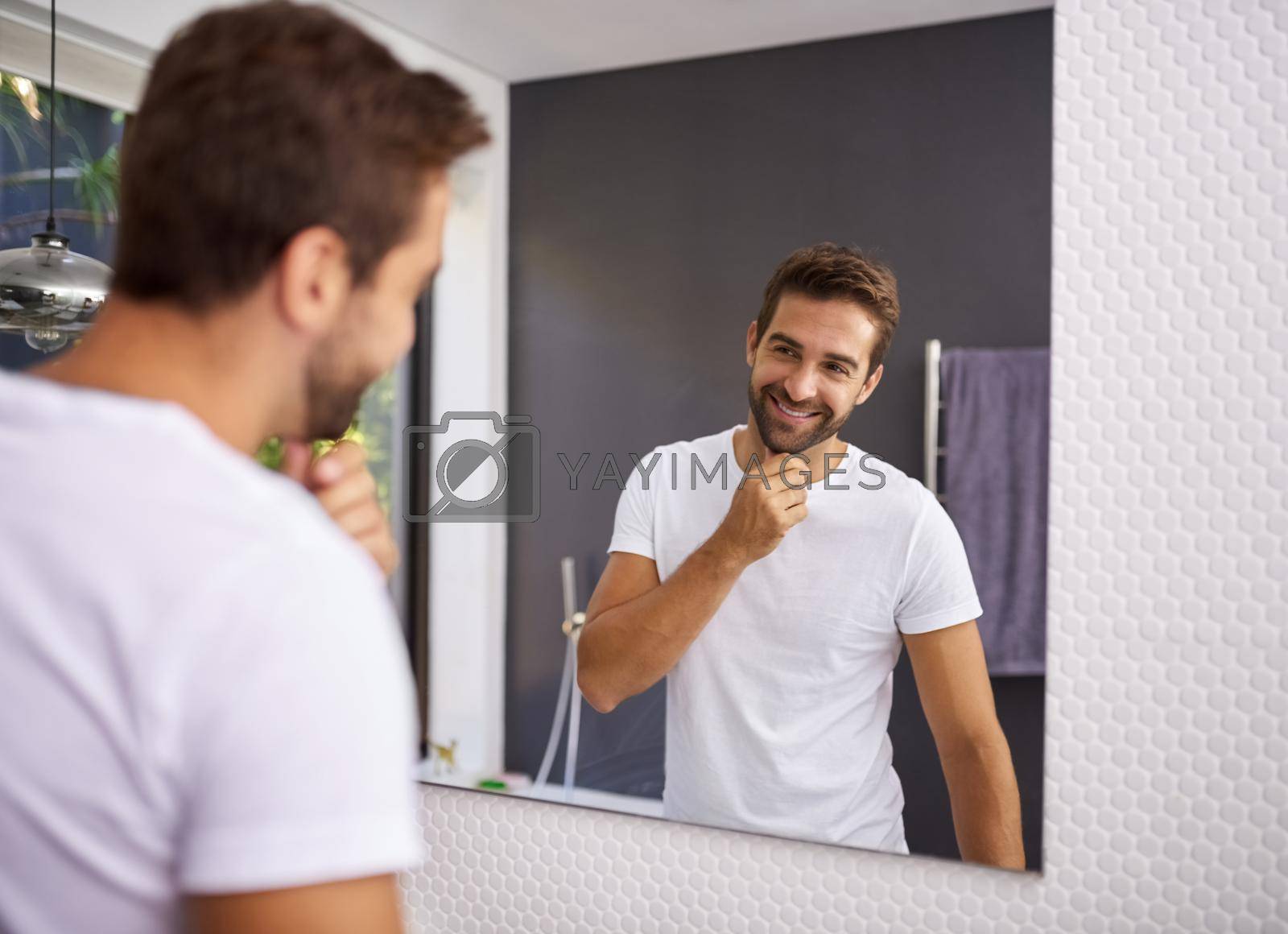 Royalty free image of I do look good with a beard though. Cropped shot of a handsome man looking at himself in the mirror whilst touching his beard at home. by YuriArcurs