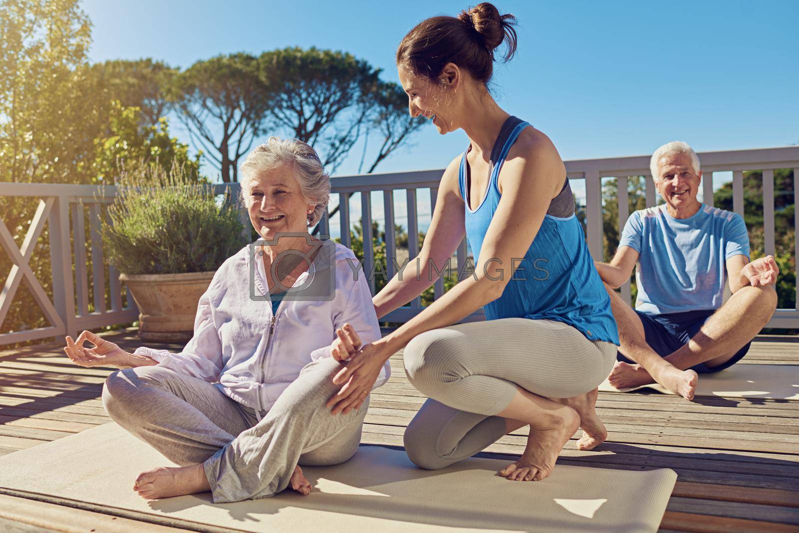 Shot of a senior couple doing yoga together with an instructor on their patio outside.