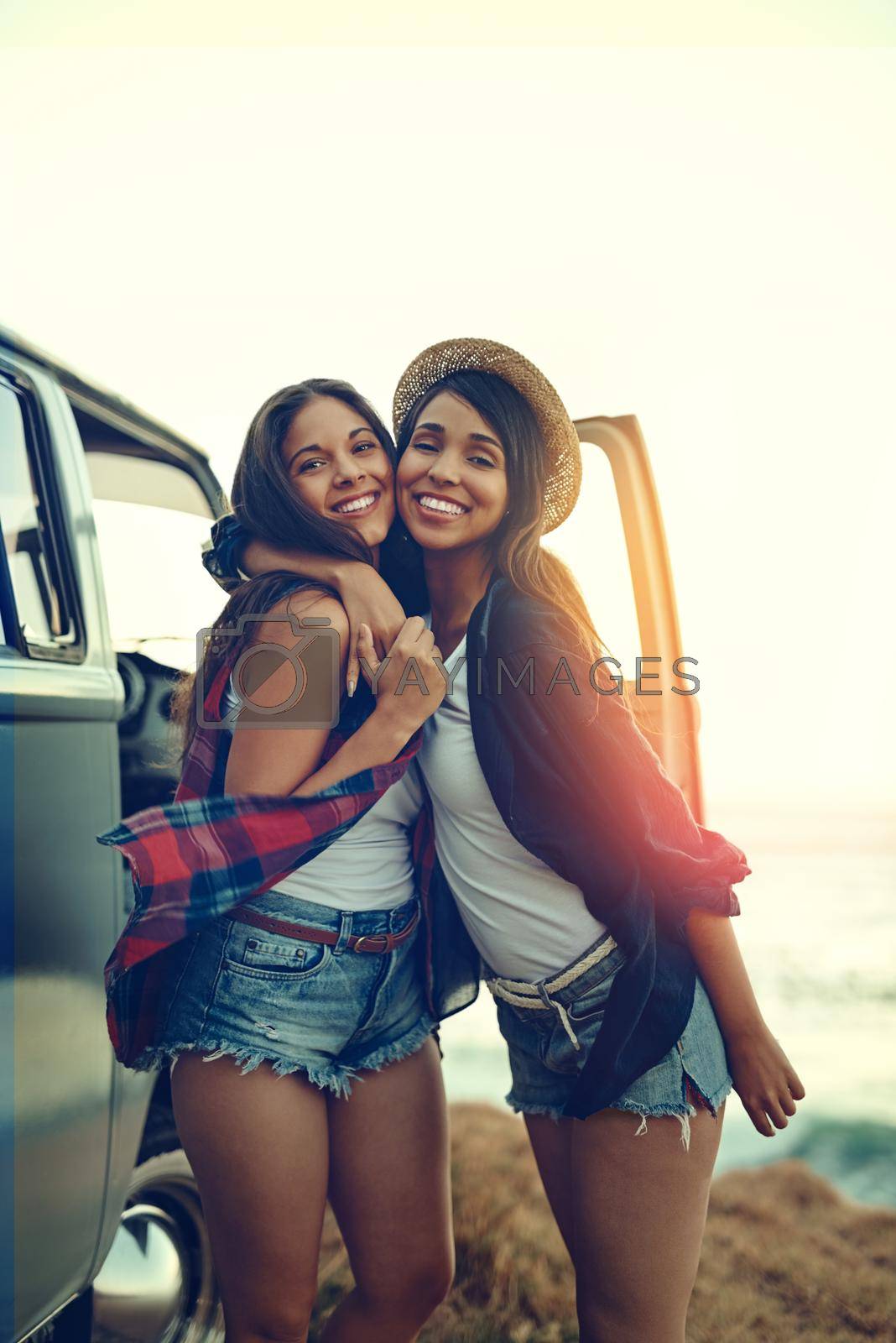 Shot of two affectionate friends stopping at the beach during their roadtrip.
