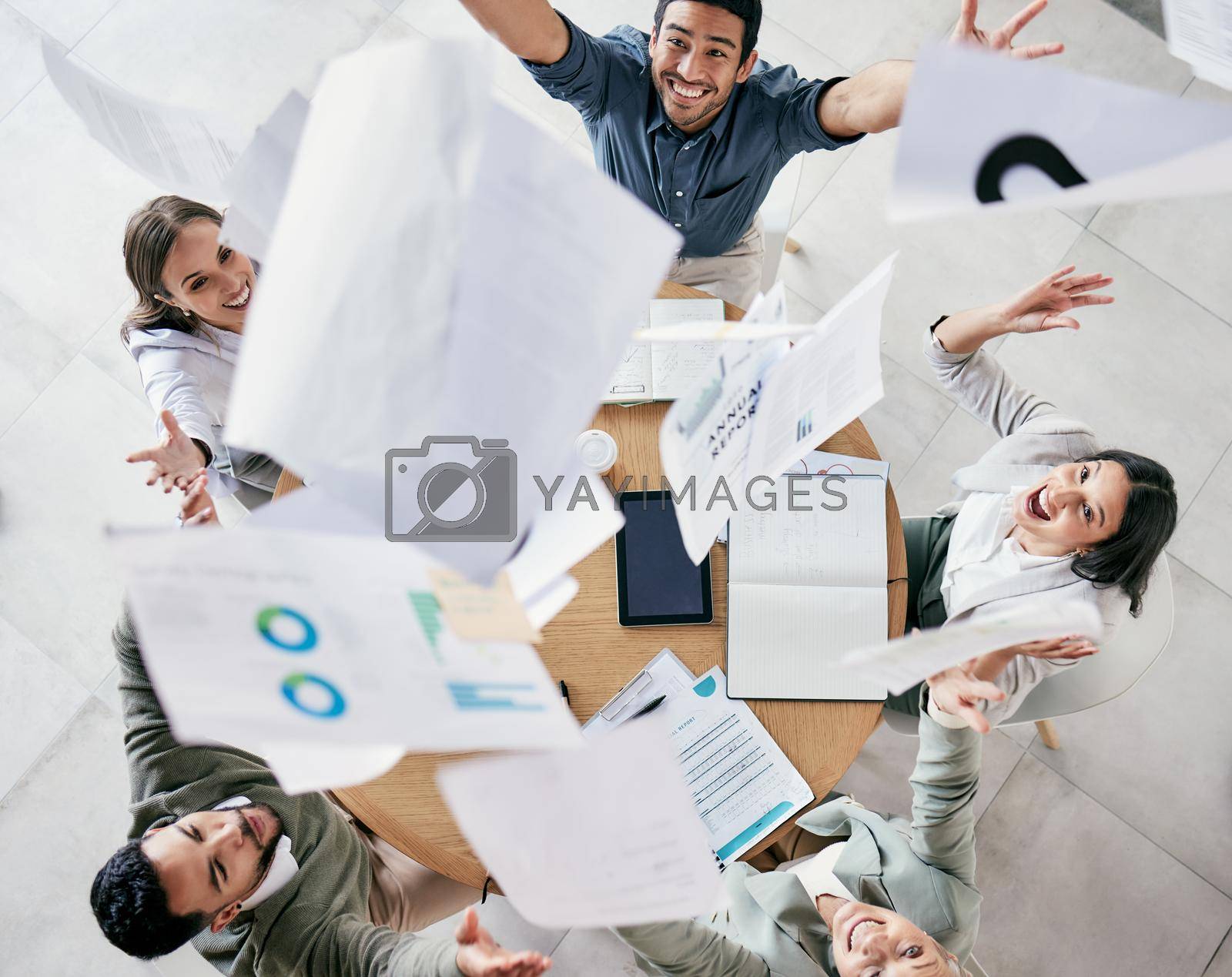 Aerial shot of a diverse group of businesspeople throwing paperwork in the air in celebration while in the office.