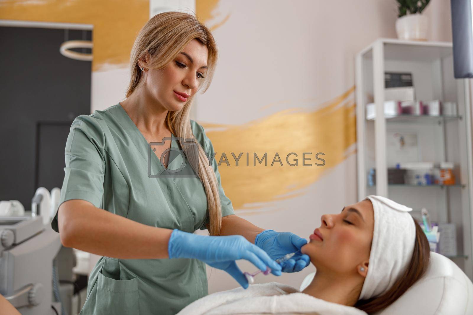 Expert beautician filling female chin with hyaluronic acid in beauty salon. Cosmetology