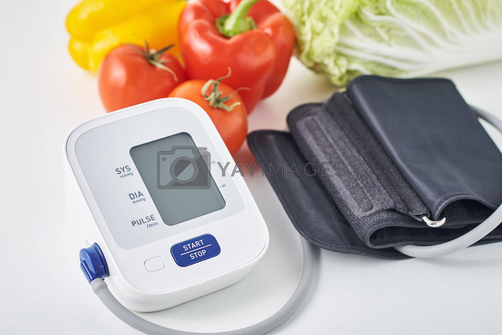 Digital blood pressure monitor and fresh vegetables on table. Healthcare concept