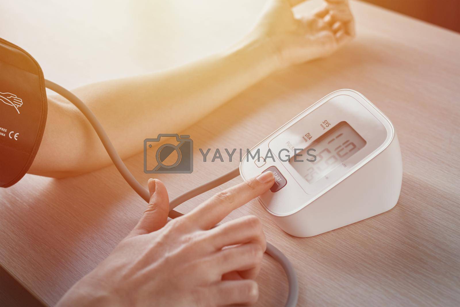 Woman measuring blood pressure with electric digital tonometer. Healthcare and medicine concept