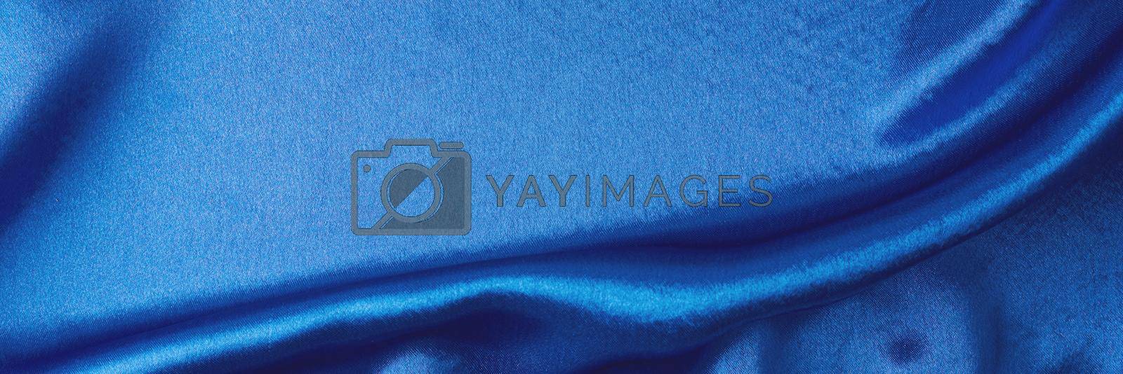Blue silk background with folds. Abstract texture of rippled satin surface, long banner