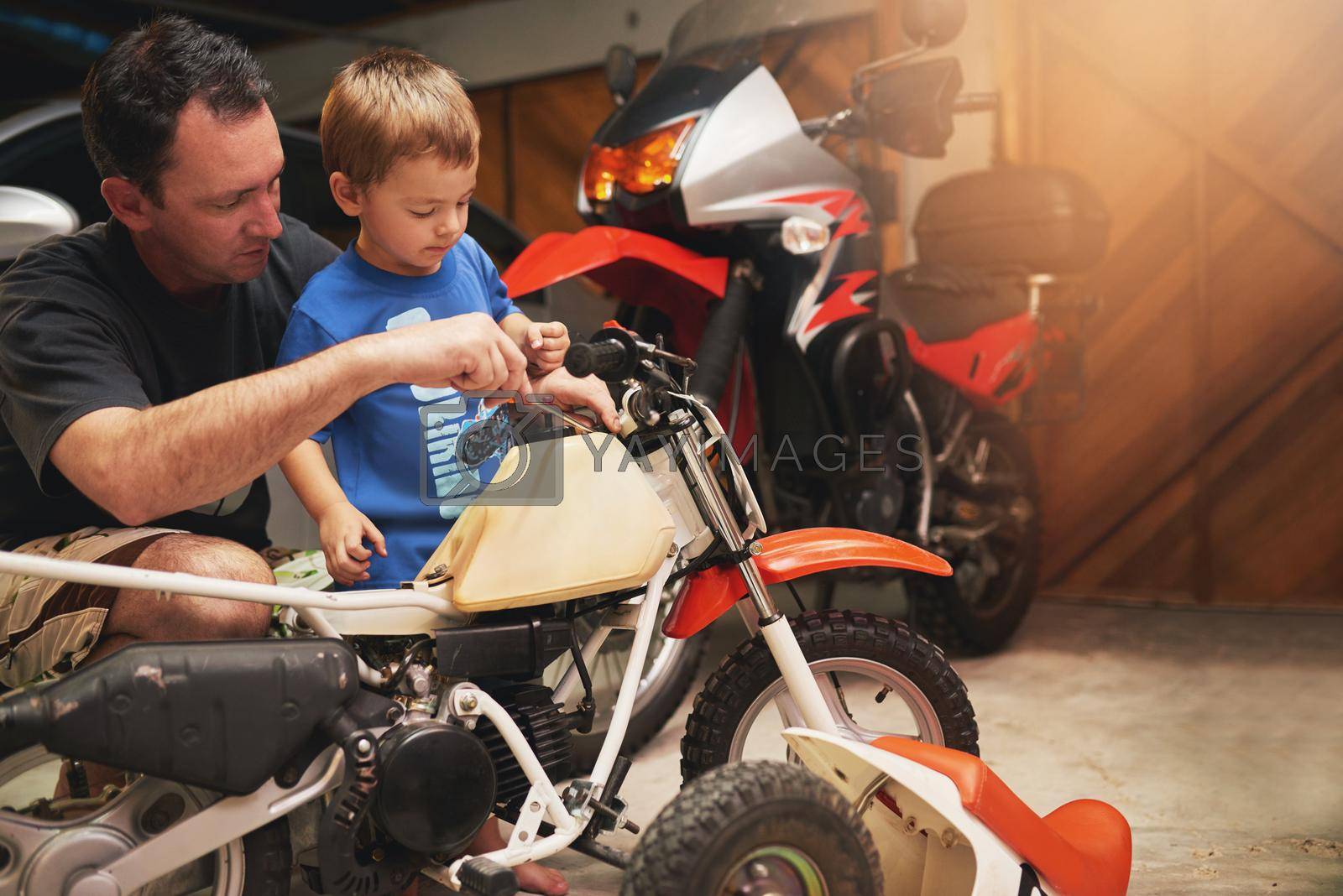 Shot of a father and son fixing a bike in a garage.