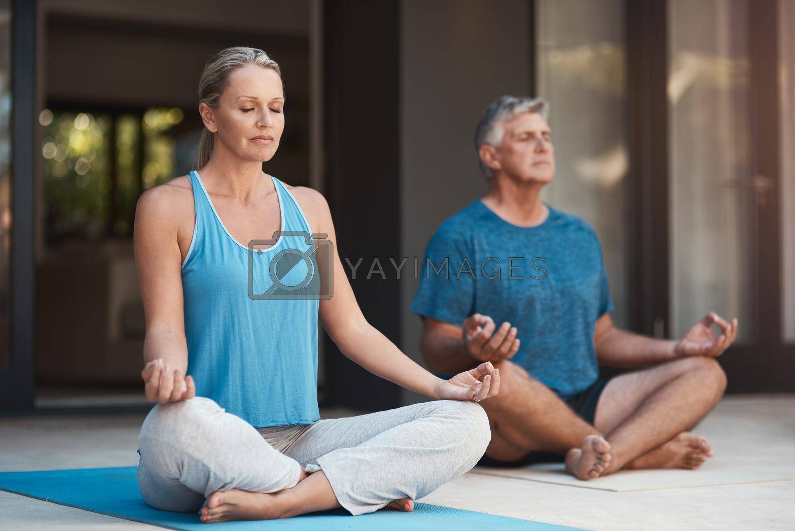 Shot of a mature couple calmly engaging in a yoga pose with their legs crossed.