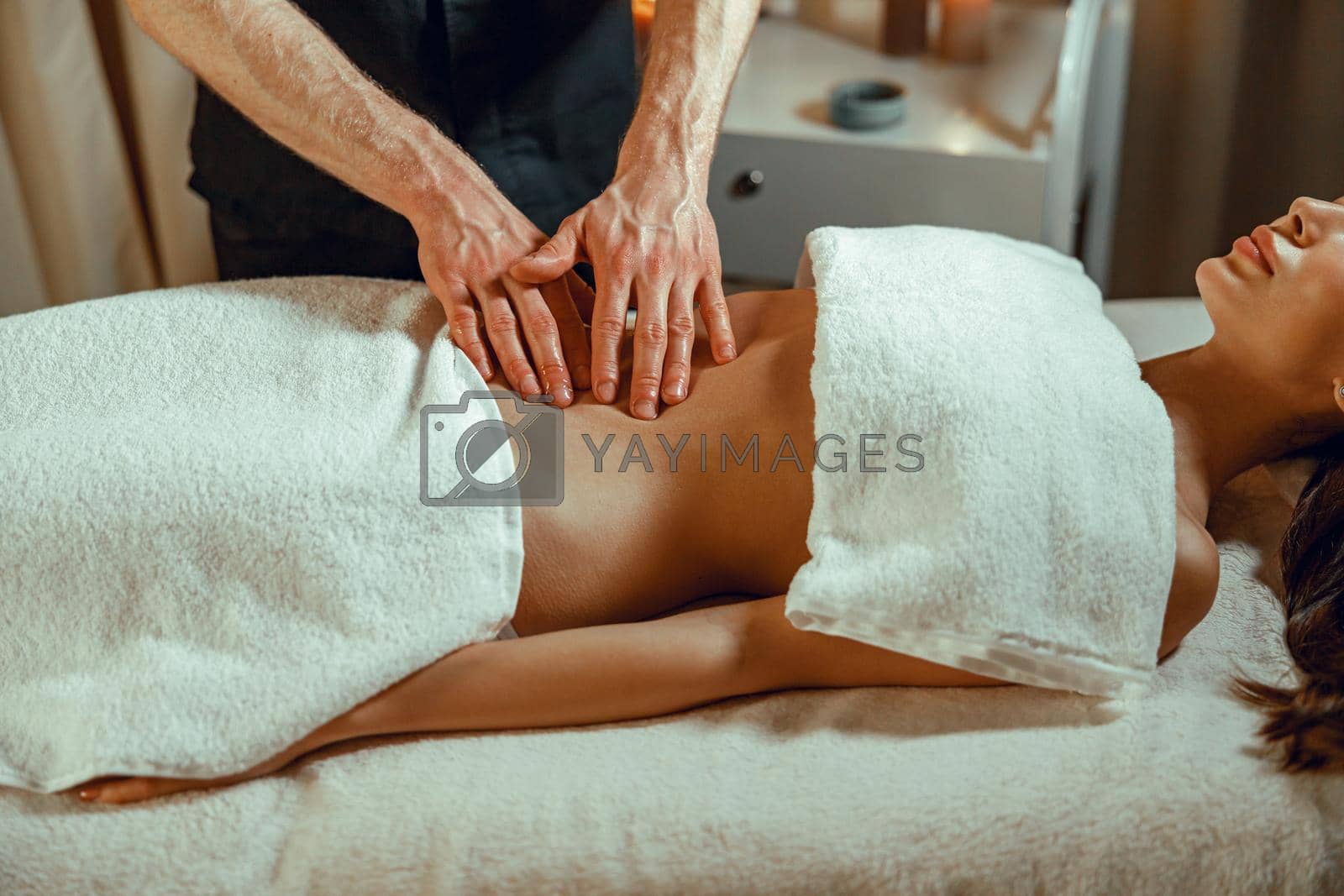 Male manual worker doing stomach massage with fingers to woman in spa salon. Therapy