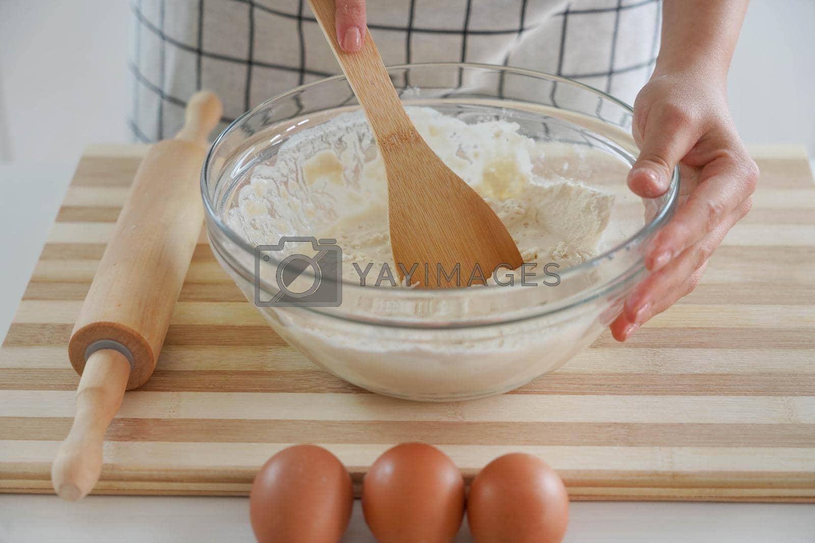Royalty free image of Woman kneads with a wooden spoon in a bowl at home, close-up by sergio_monti