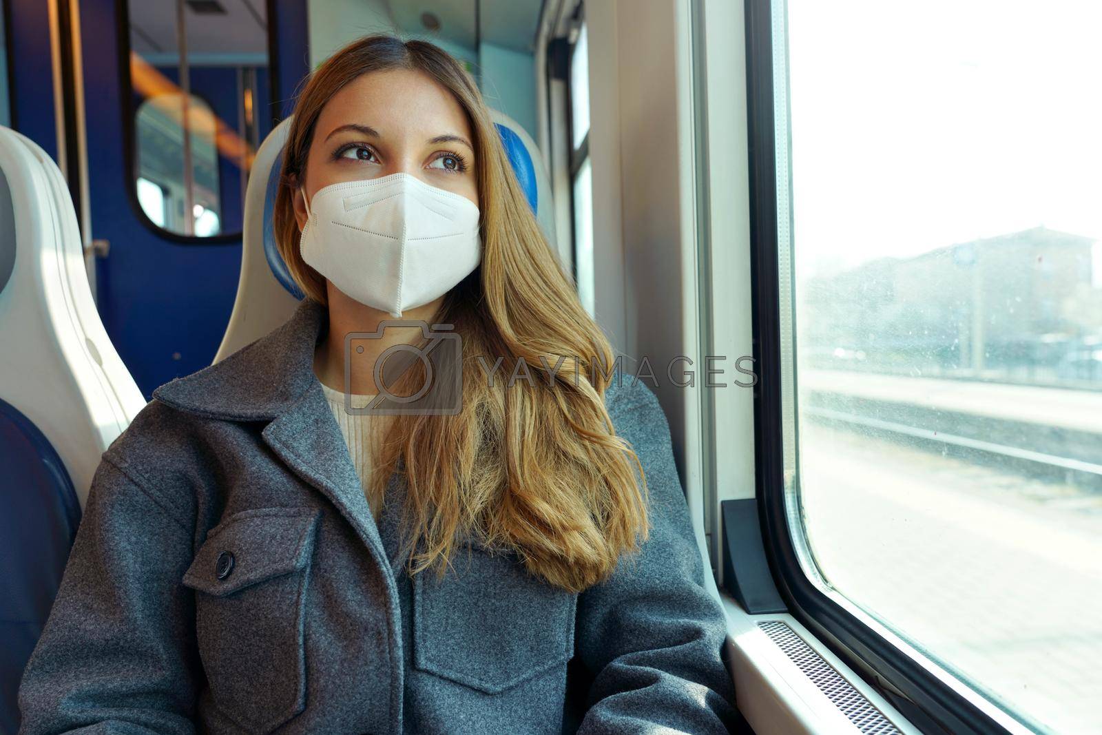 Protective mask mandatory on public transport. Portrait of young woman traveling on train looking through the window.