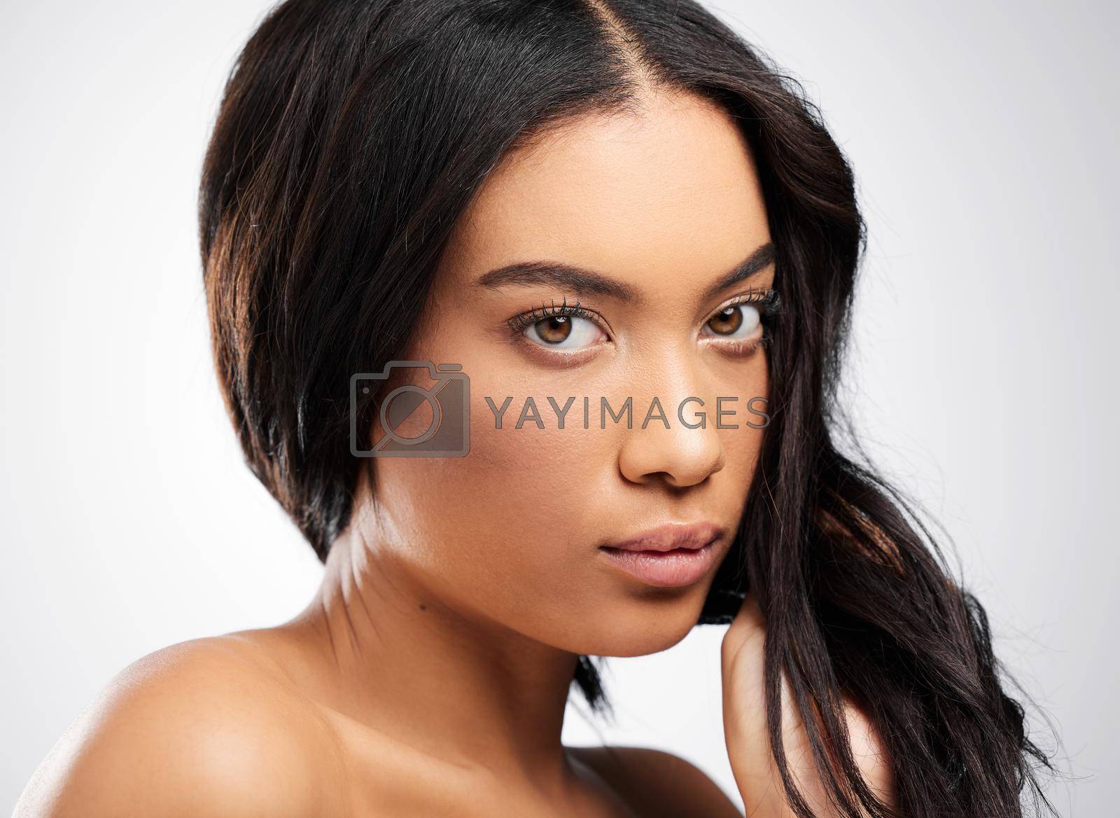 Royalty free image of Youve gotta take your haircare seriously. Cropped portrait of an attractive young woman posing in studio against a grey background. by YuriArcurs