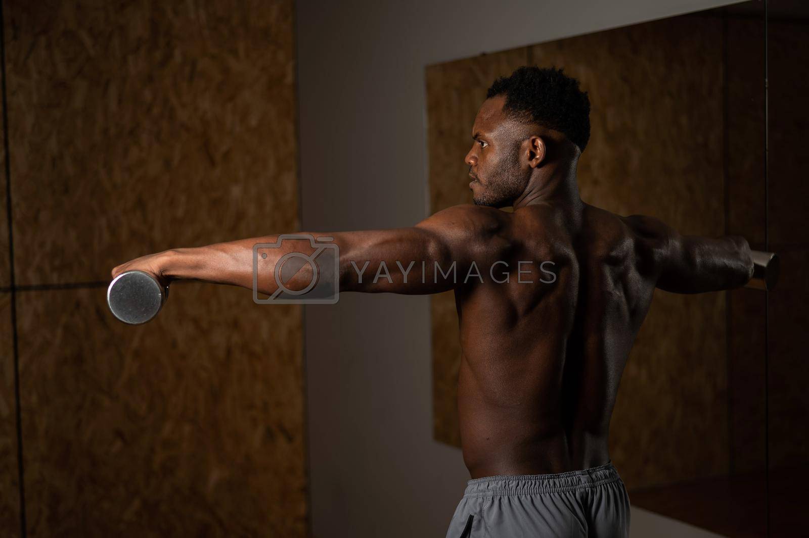 Royalty free image of Attractive african american man doing arm exercises with dumbbells. by mrwed54
