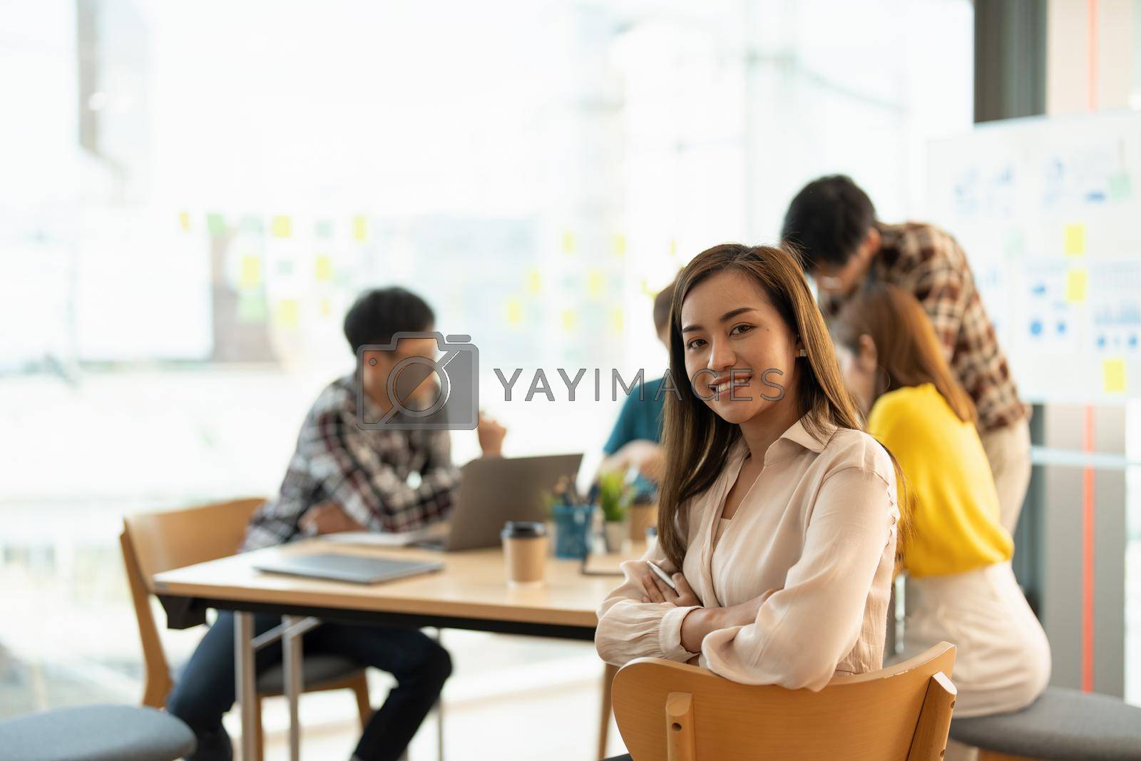 Attractive young Asian business woman smiling and looking over shoulders at business meeting with co-workers.