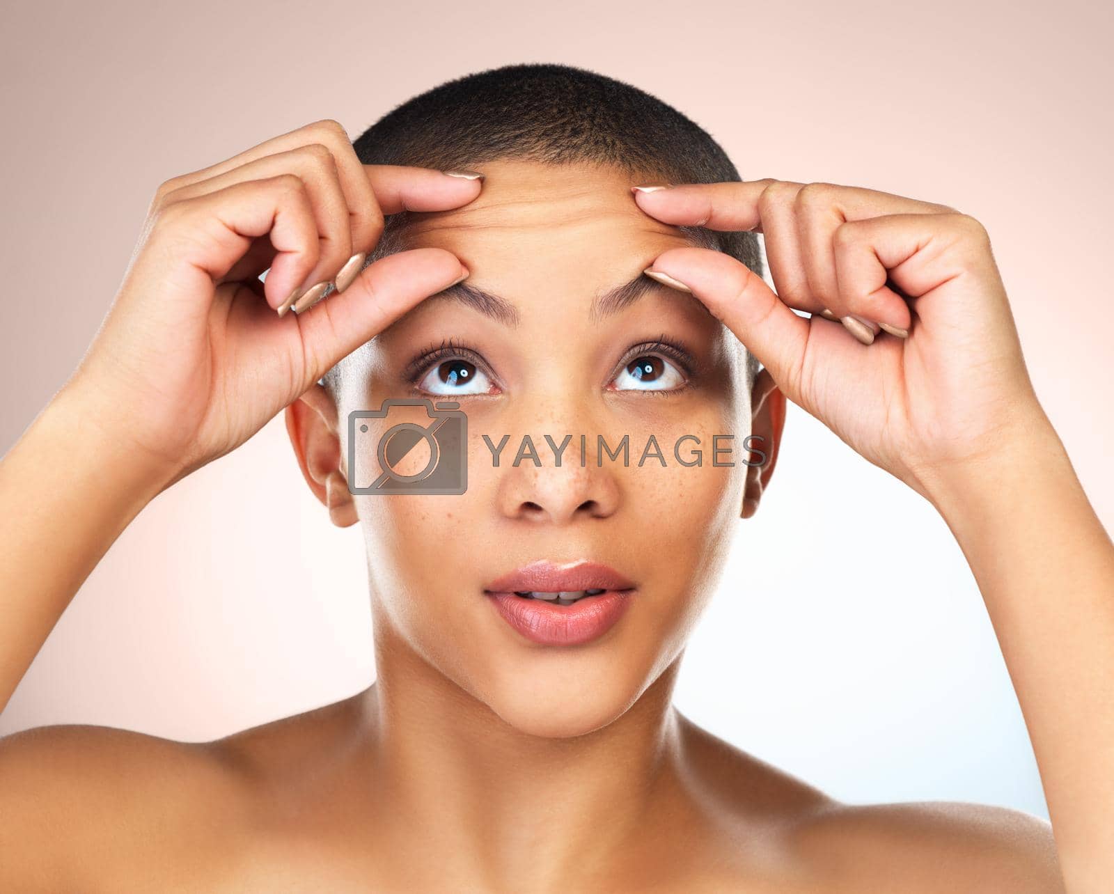 Royalty free image of How do I get rid of it. Studio shot of a beautiful young woman squeezing her forehead against a grey background. by YuriArcurs