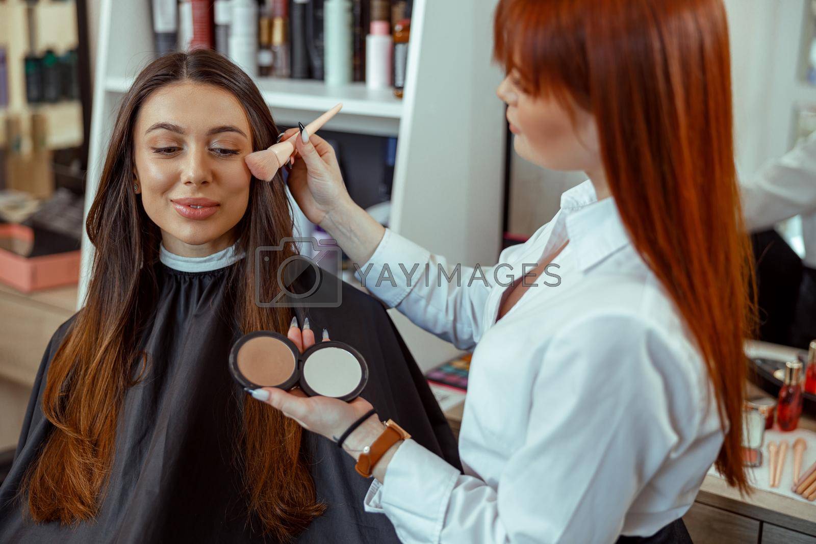 Professional makeup artist applying bronzer powder with a brush. Beauty salon services