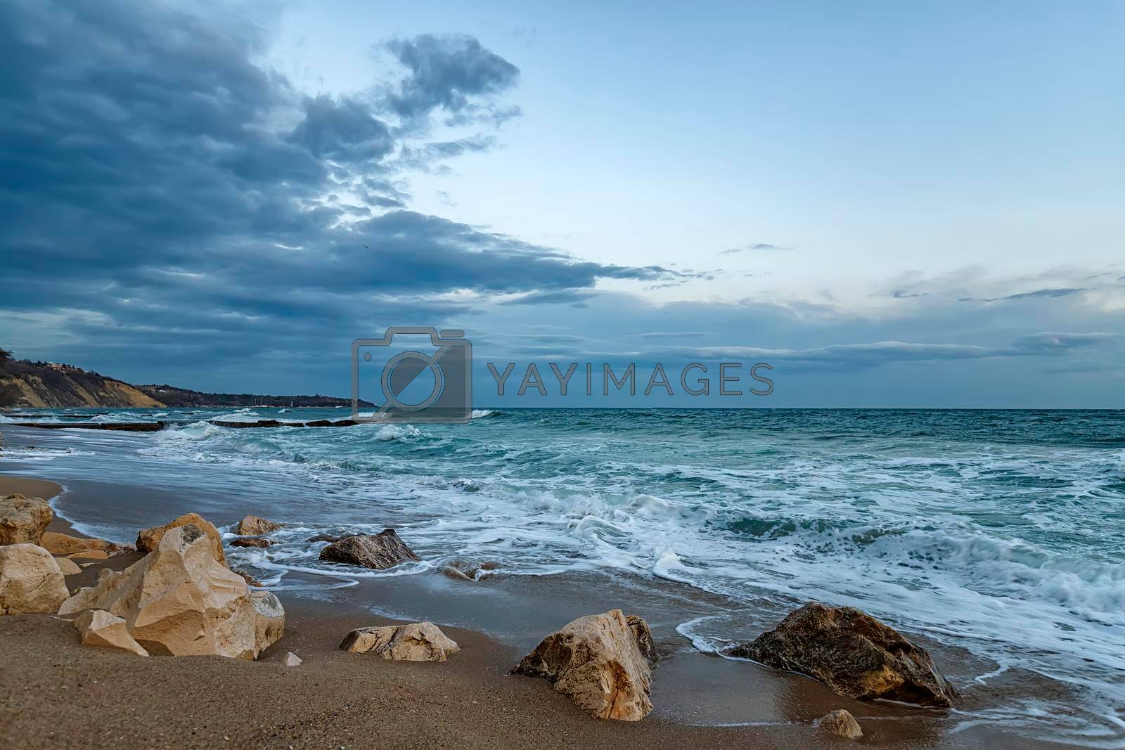 Beauty cloudy seascape with waves flowing between rocks.