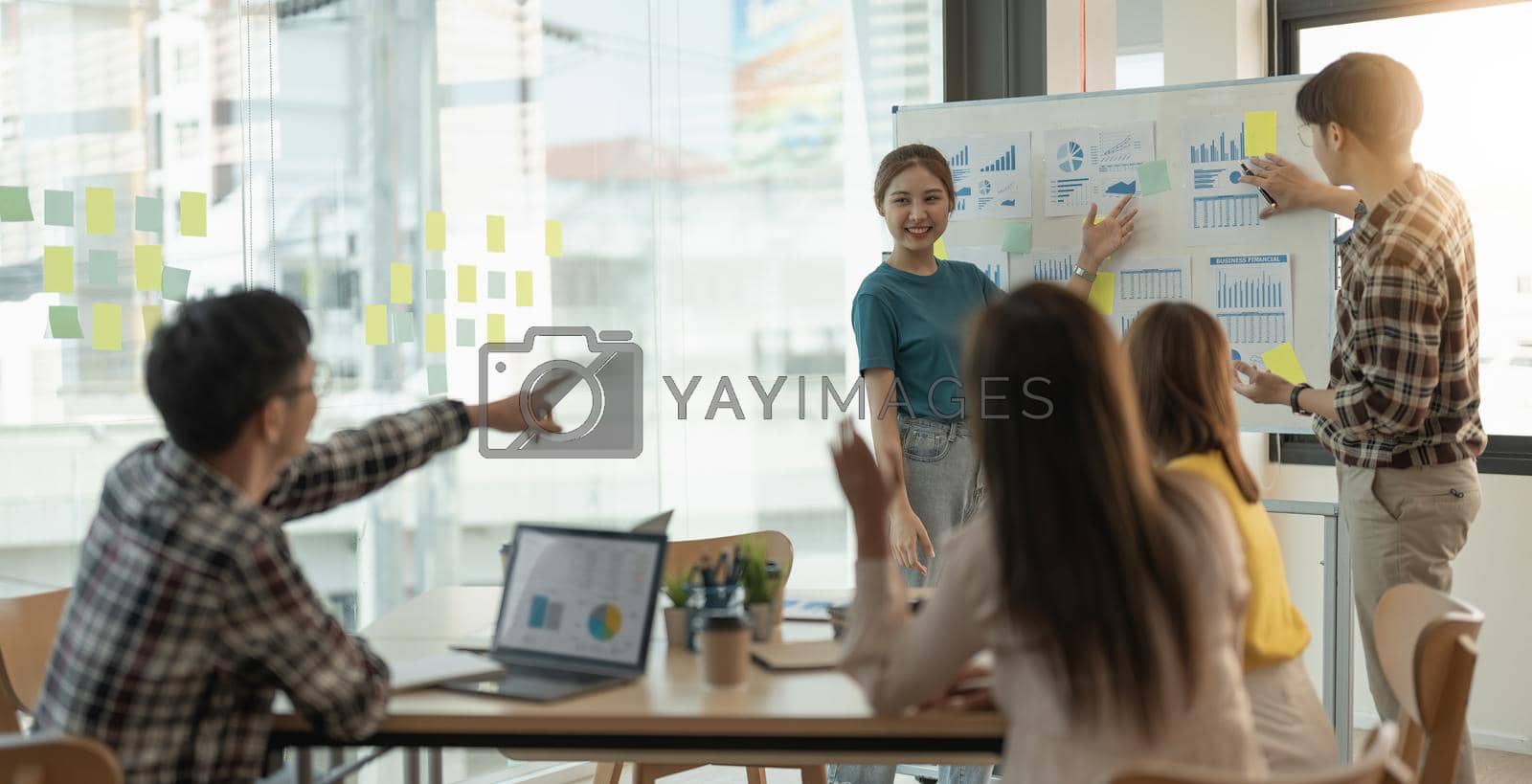 Royalty free image of group of young creative asian people doing brainstorming meeting colleagues in board room discussing project. woman standing at white board give presentation by nateemee