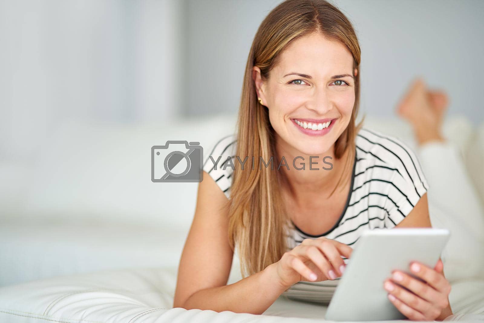 Royalty free image of Its just so easy to stay connected nowadays. Shot of a young woman browsing the internet at home. by YuriArcurs