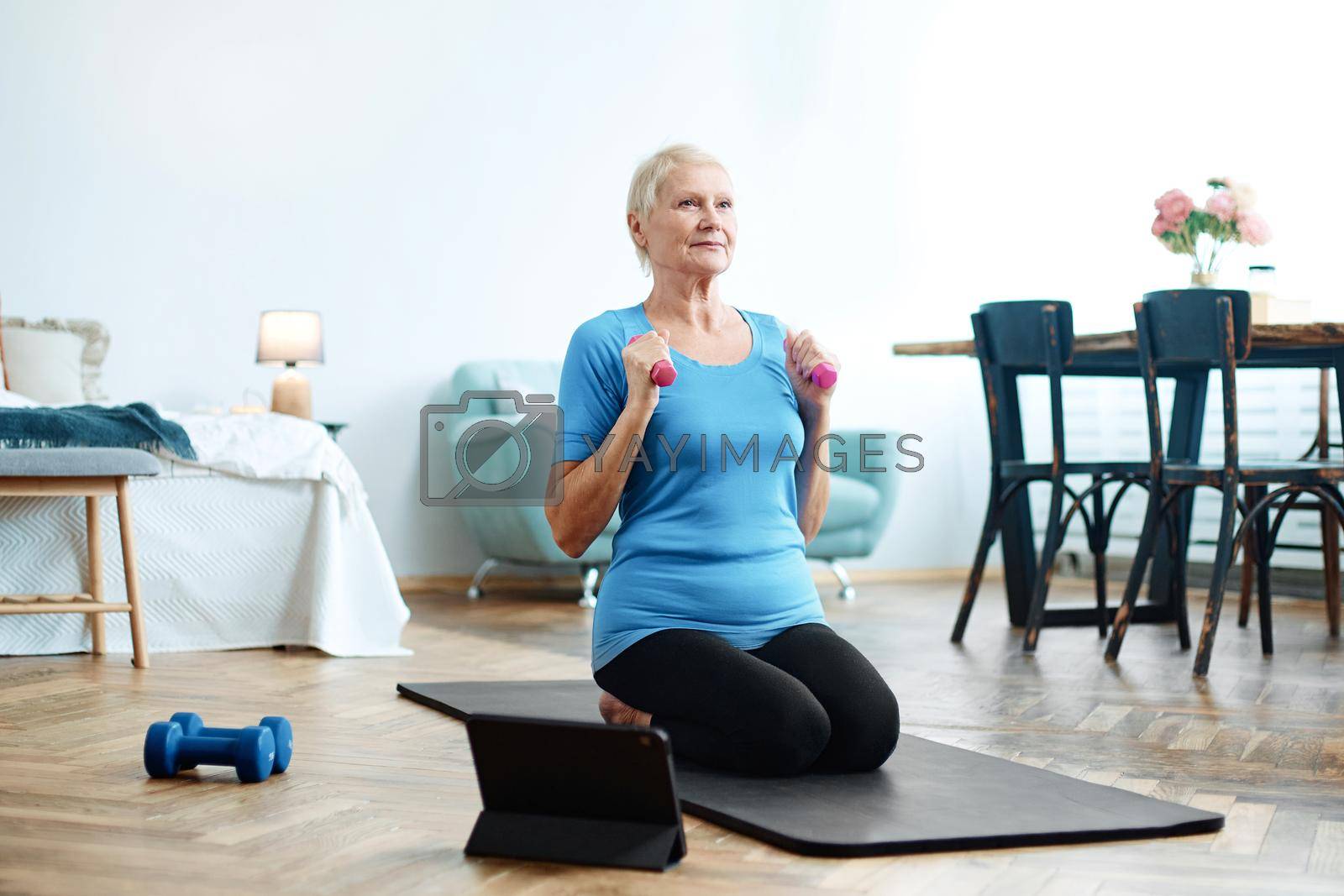 elderly woman sitting in a yoga pose in front of an open laptop. concept of online training.