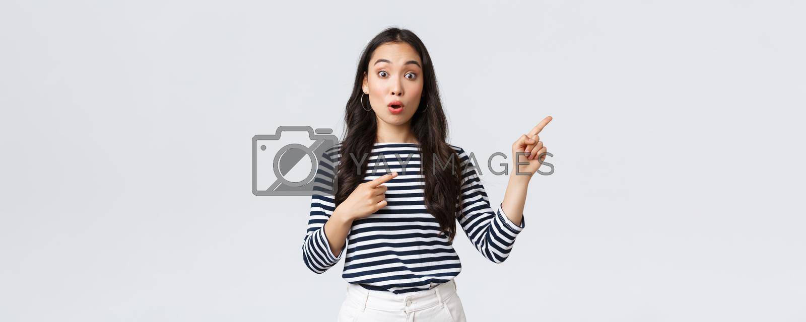 Lifestyle, beauty and fashion, people emotions concept. Surprised and intrigued attractive asian woman customer pointing fingers upper right corner, say wow amazed, found awesome product.