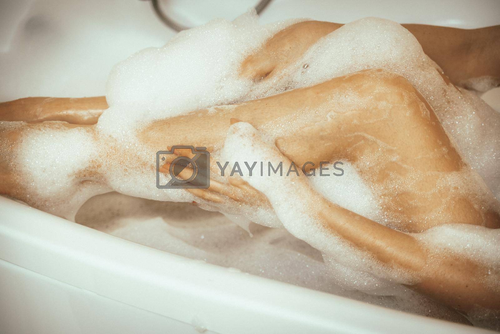 Women's feet in bath foam. View from above. Enjoy and relax in a spa hotel.