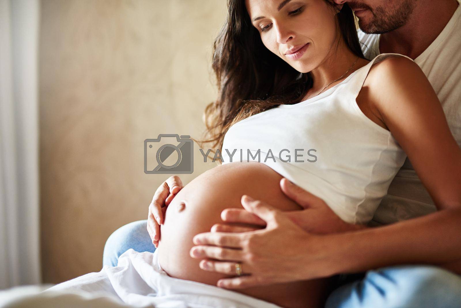 Shot of a husband and pregnant wife sitting together in a bedroom.