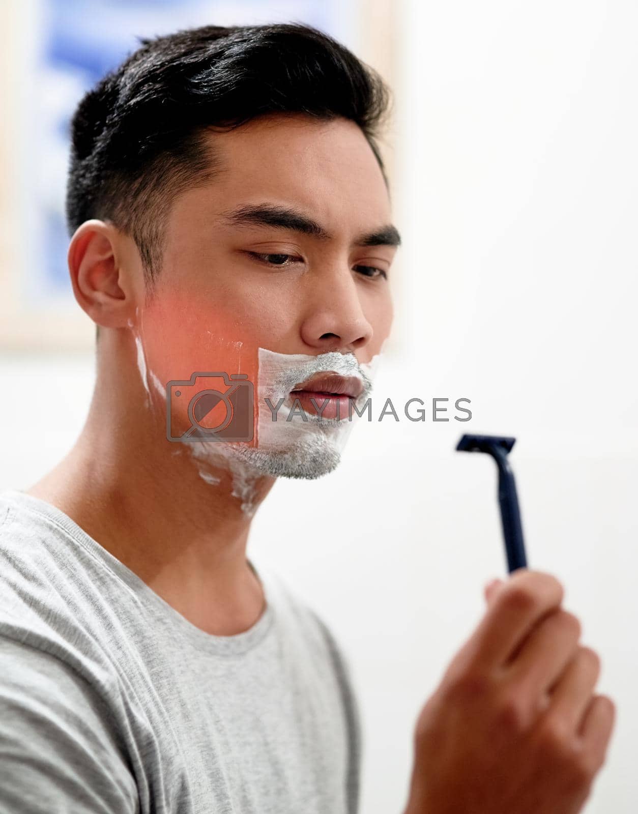 Royalty free image of I really need to replace this. Shot of a young man at home getting razor burn on his face from shaving with a disposable razor. by YuriArcurs