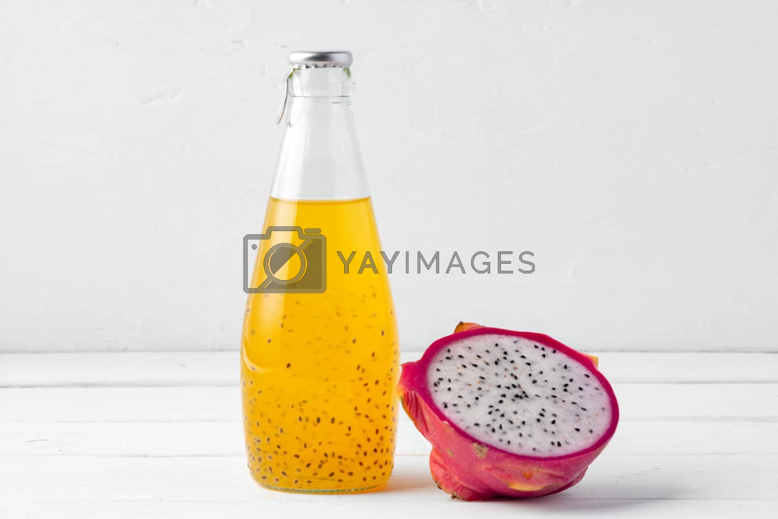 Glass bottle of dragon fruit drink on white background, close up