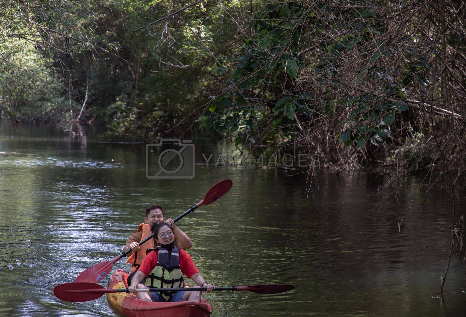 Nakhon Ratchasima, Thailand. Mar - 20, 2022 : Woman and man adventurous people having fun together while red kayaking on brook in forest. Having fun in leisure activity, Nature and Tourist attraction concept. Selective focus.