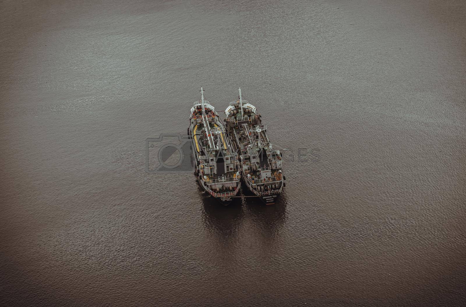 Bangkok, Thailand - 22 Mar, 2022 : Two cargo ships parked in the middle of the Chao phraya river on water background. Copy space, Selective focus.