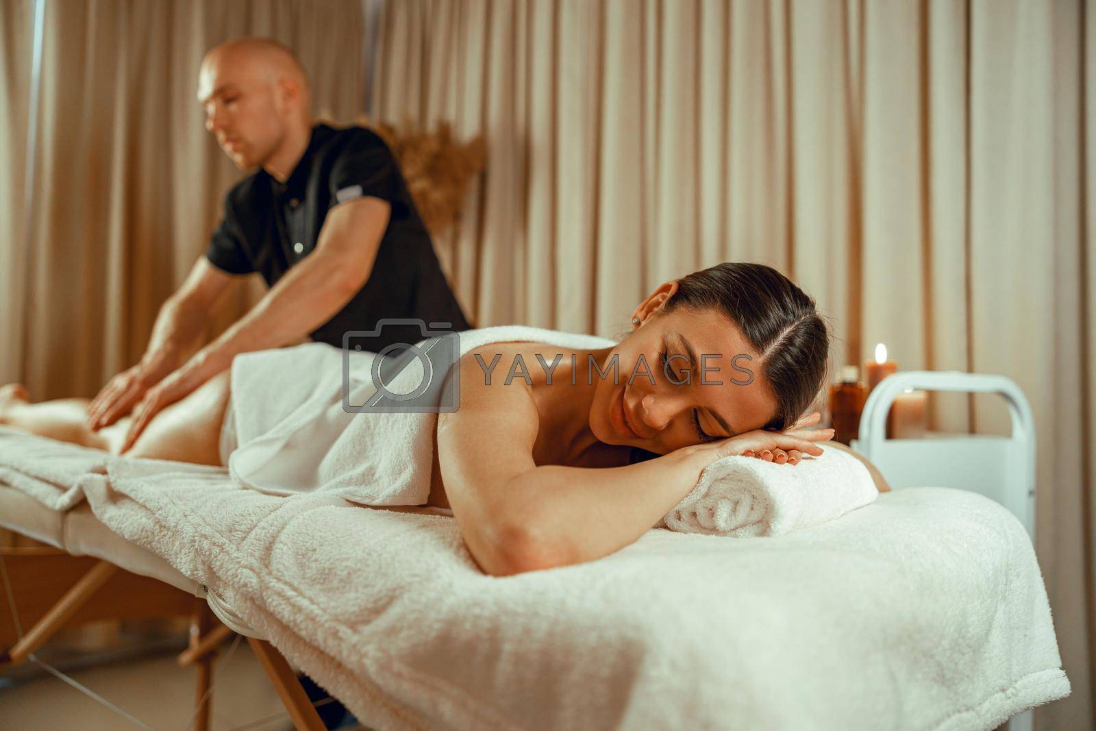 Woman lying with eyes closed, enjoying professional massage at spa center. Resort, relax concept