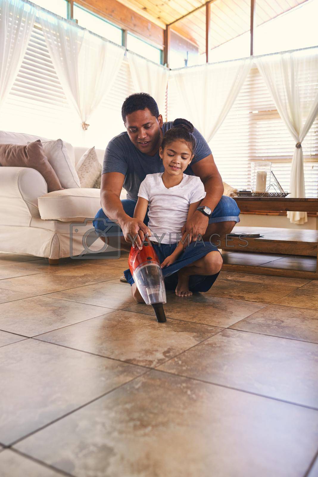 Shot of a father and daughter vacuuming the floor.