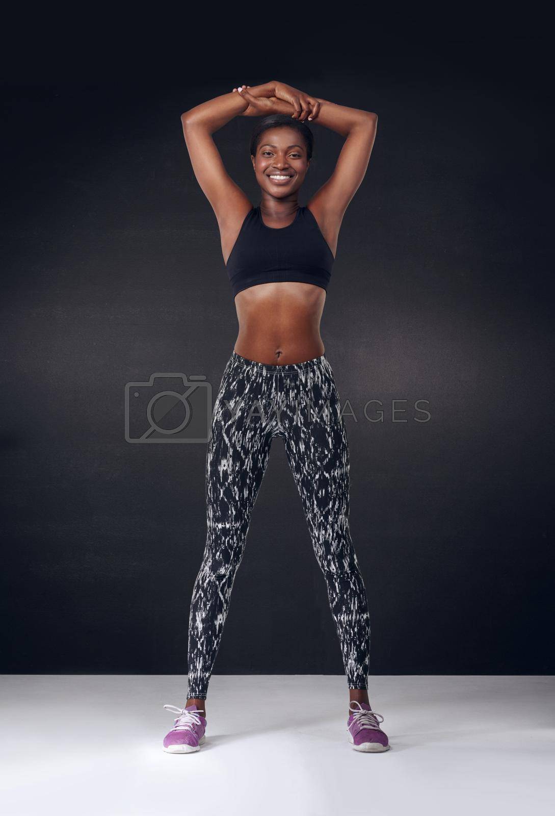 Royalty free image of Proud of the body Ive achieved. Studio shot of a beautiful young woman stretching against a black background. by YuriArcurs