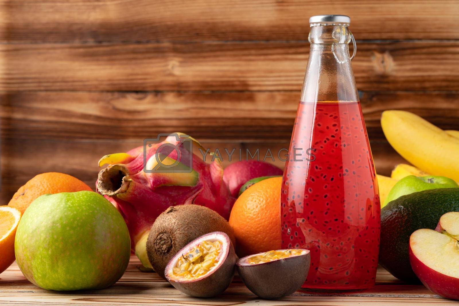 Fruit drink in glass bottle and frsh fruits on wooden background, close up