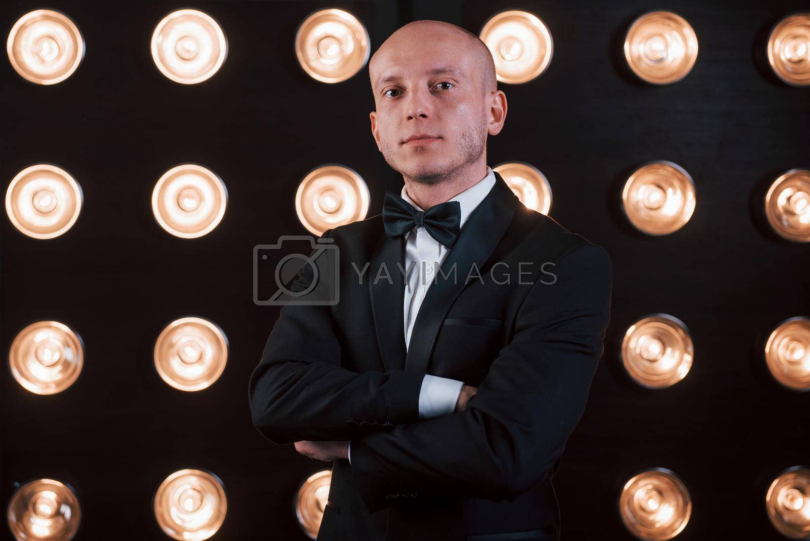 Royalty free image of Nice portrait of professional illusionist. Magician in black suit standing in the room with special lighting at backstage by Standret