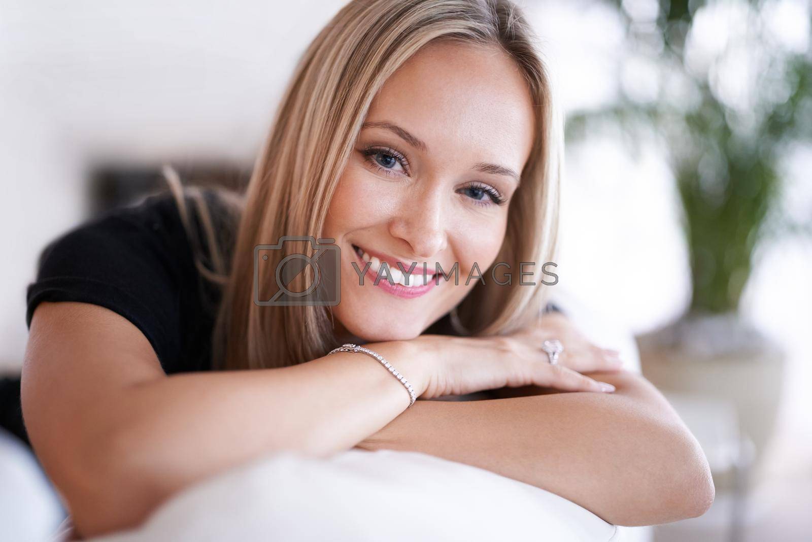 Royalty free image of Her smile radiates warmth. Portrait of a young blonde woman relaxing on the sofa at home. by YuriArcurs