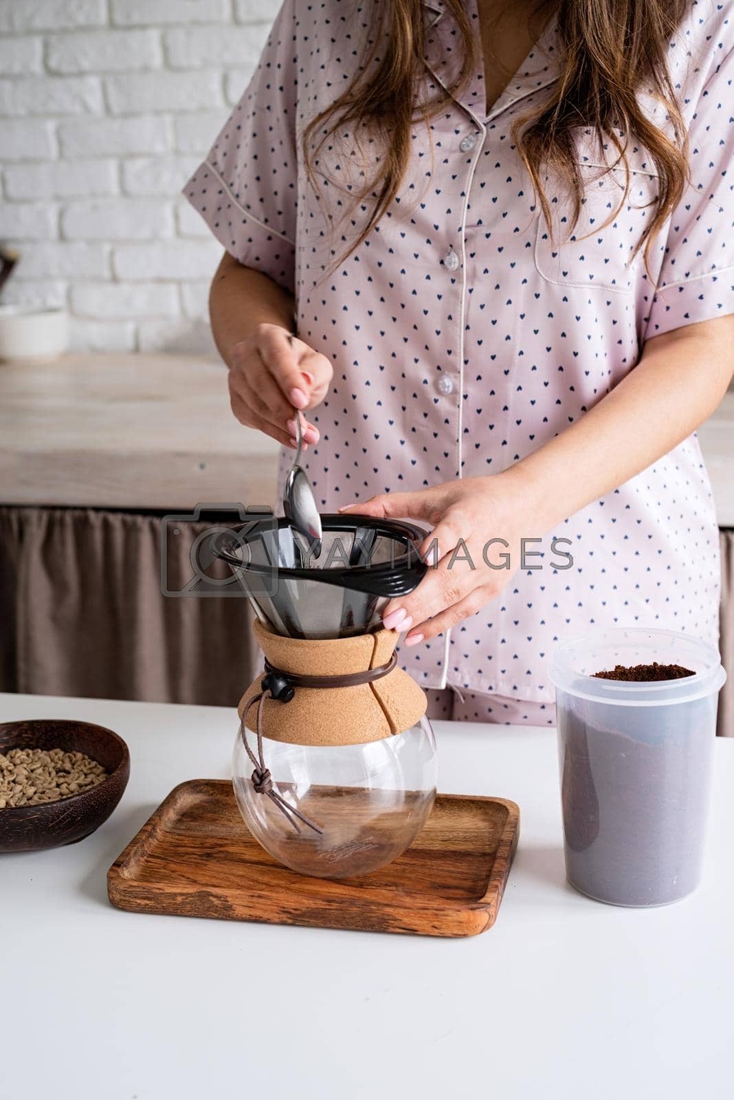 Royalty free image of young woman in lovely pajamas making coffee at home kitchen by Desperada