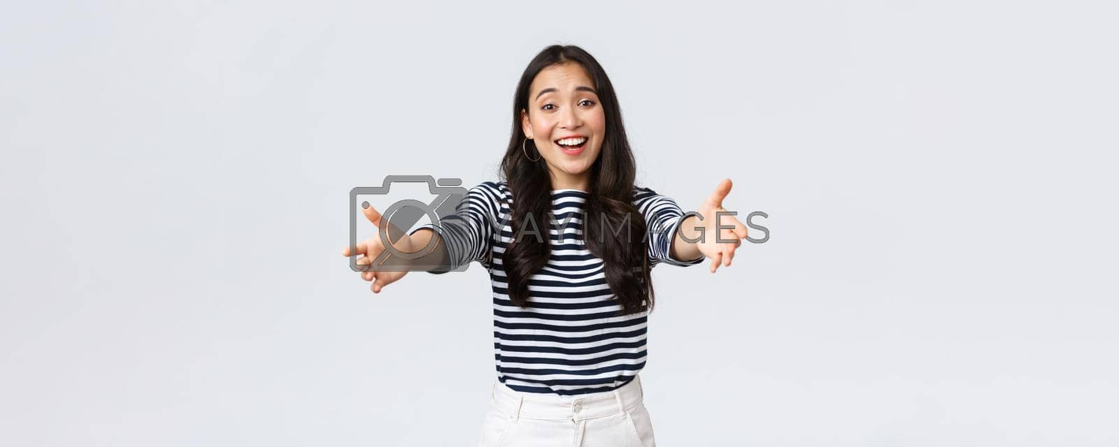 Lifestyle, people emotions and casual concept. Friendly charming asian girl reaching hands forward to hold something, giving hug or embracing, standing white background.