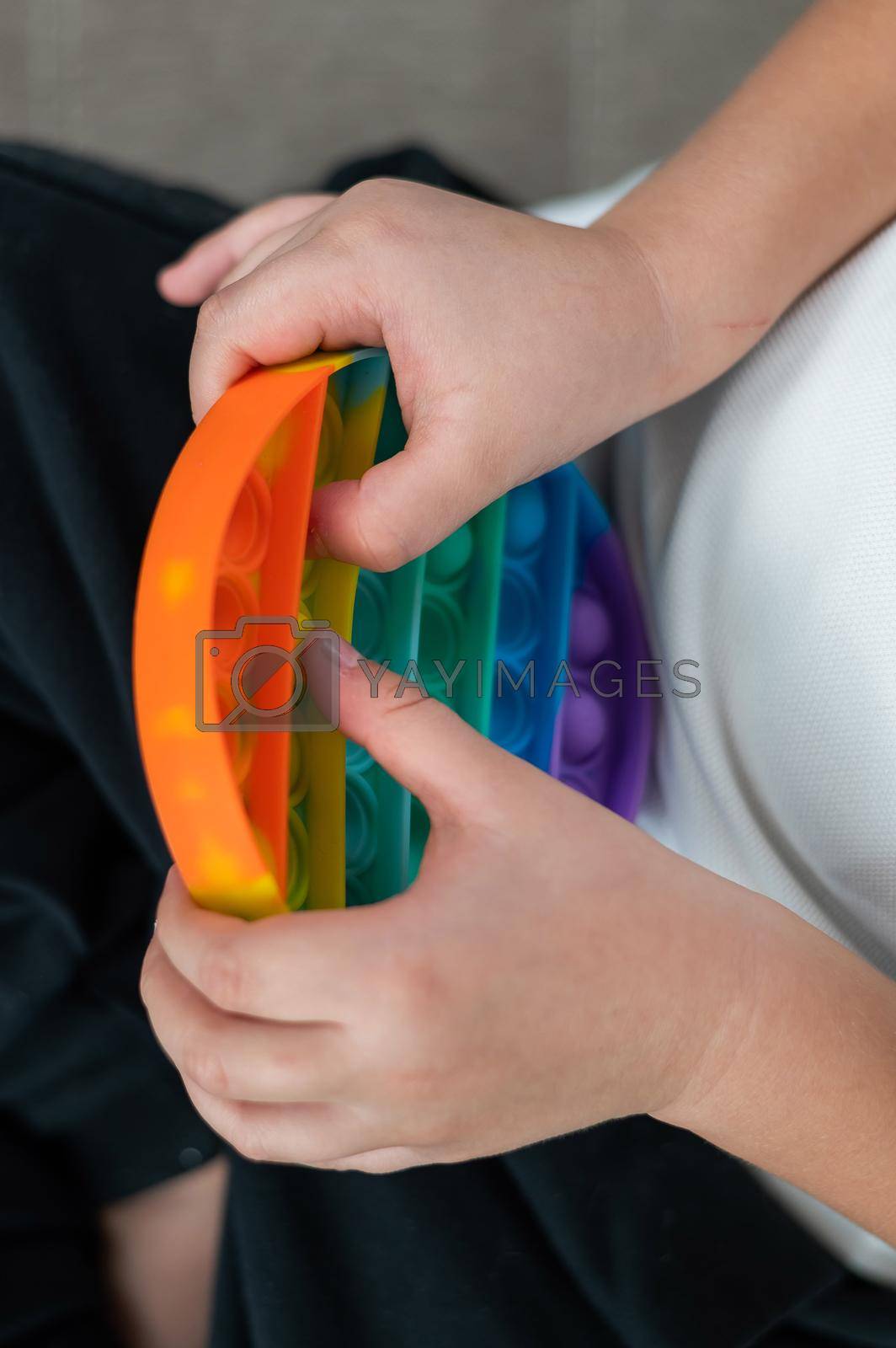 Royalty free image of Faceless little boy playing pop it rainbow colors. by mrwed54