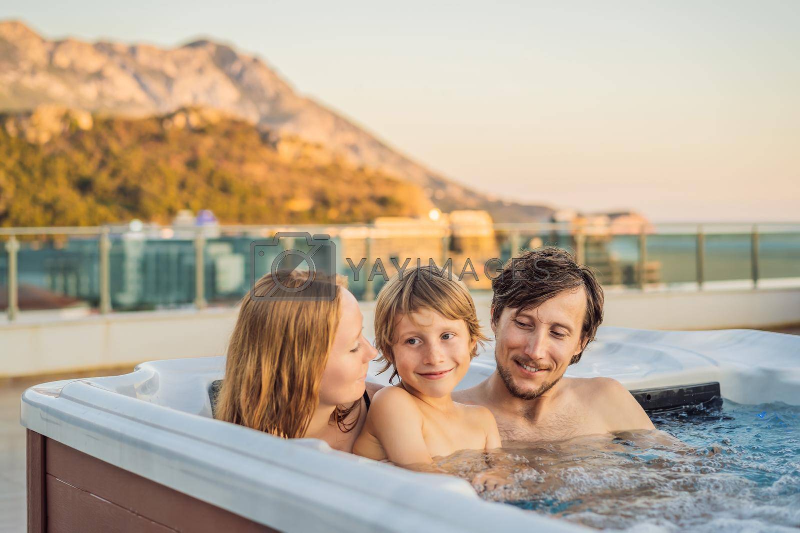 Royalty free image of Portrait of young carefree happy smiling happy family relaxing at hot tub during enjoying happy traveling moment vacation. Life against the background of green big mountains by galitskaya
