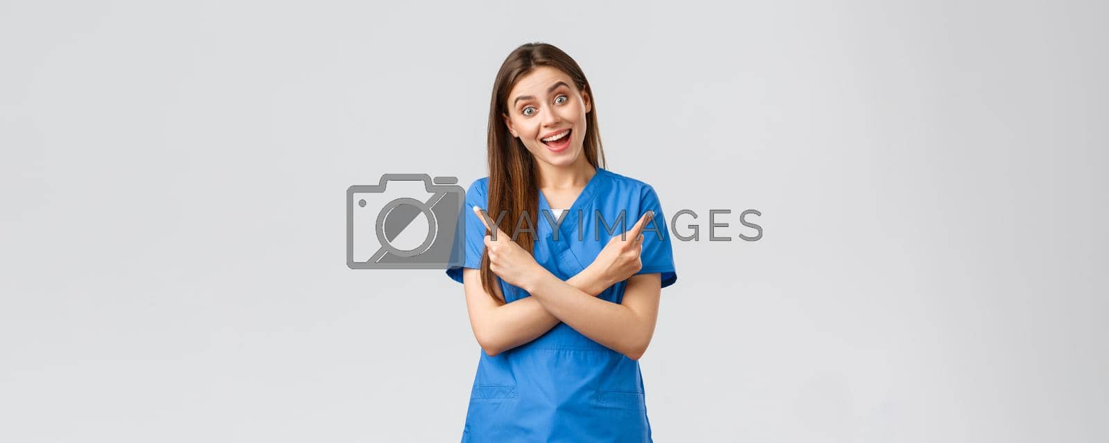 Healthcare workers, prevent virus, insurance and medicine concept. Enthusiastic smiling female nurse, doctor in blue scrubs, pointing fingers sideways left right, showing two products or banners.